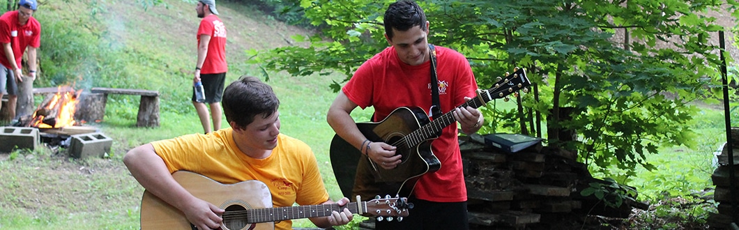Camp counselor and camper playing guitar together