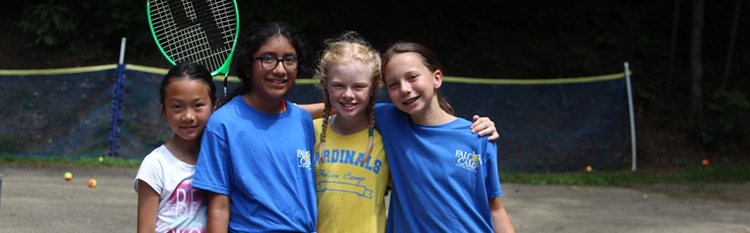 Young girls learning tennis at summer camp