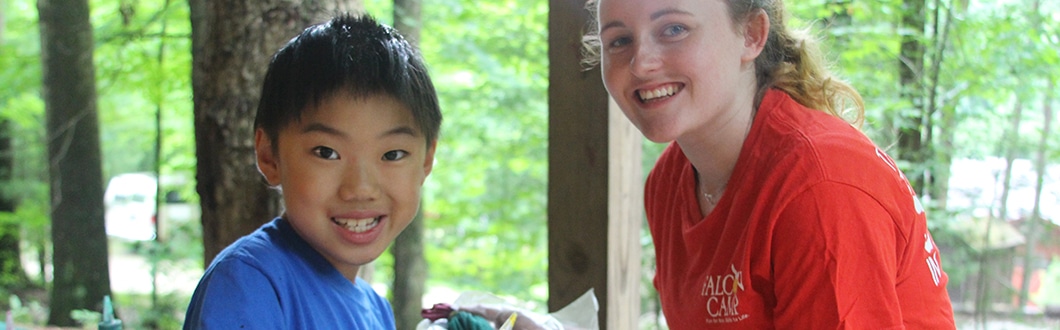 Camp counselor with young boy camper smiling