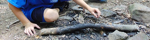 Young boy learning how to start a fire at summer camp