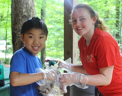 Camp instructor and boy preparing food at summer camp