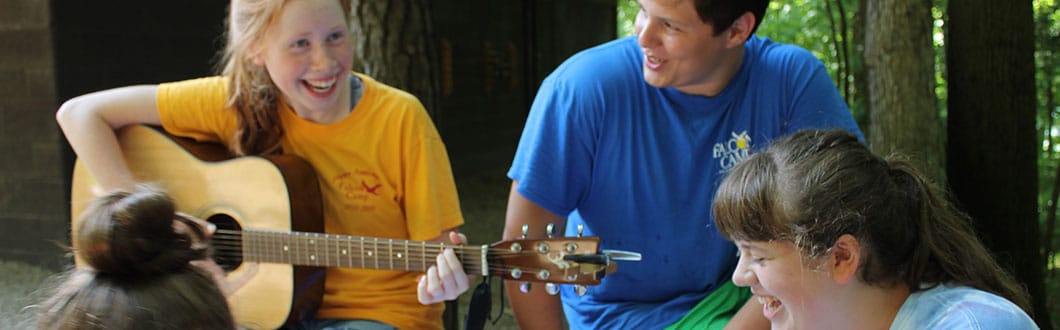 Campers playing guitar and laughing together