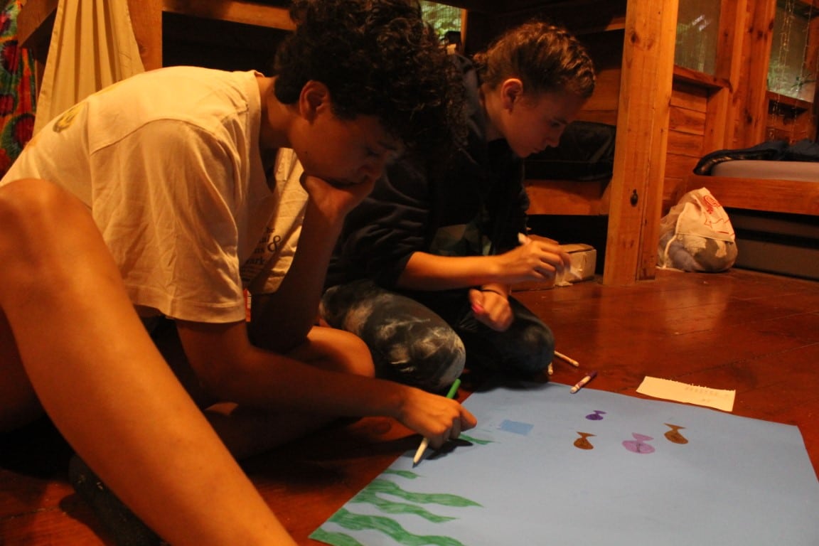 Campers in cabin doing art
